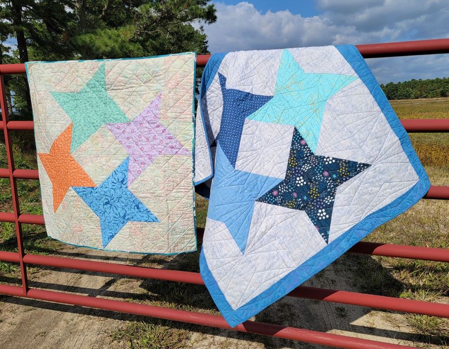 two quilts hanging over a fence